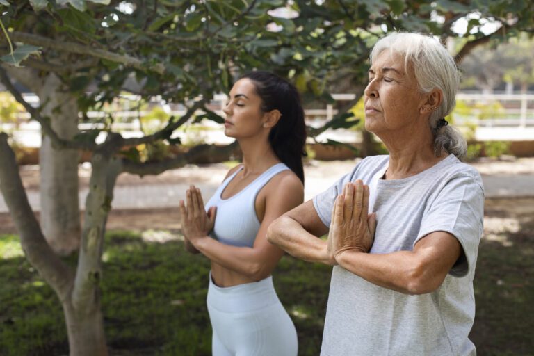 Senior doing yoga with caregiver in the park
